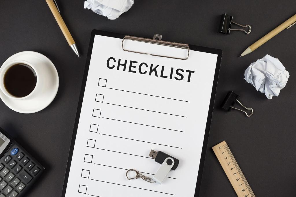 Organized clipboard checklist with pen, smartphone, and tools on a clean work surface